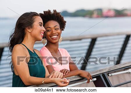 Stock Image - Young women chatting on bridge. Fotosearch