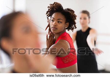 Stock Image - "Young women dancing looking away, differential focus". Fotosearch