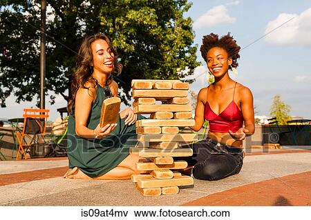 Stock Photo - Young women playing with building blocks on floor. Fotosearch