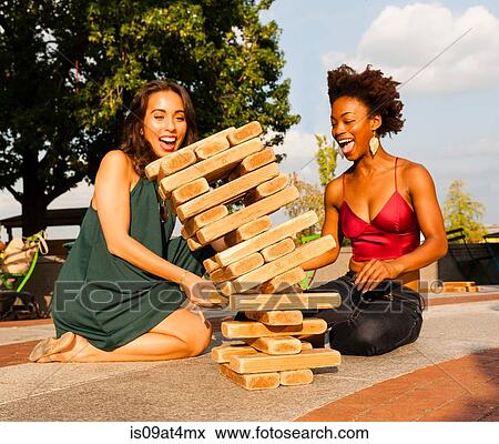 Stock Photo - Young women playing with building blocks on floor. Fotosearch