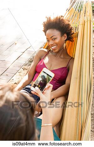 Young women taking photograph in hammock View Large Photo Image Picture - Young women taking photograph in hammock. Fotosearch