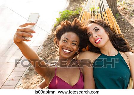 Young women taking selfie in hammock View Large Photo Image Picture - Young women taking selfie in hammock. Fotosearch