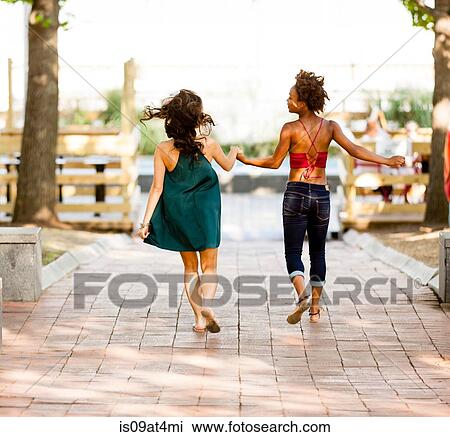 Stock Image - Young women walking on cobbled street. Fotosearch