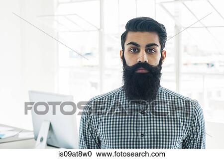 Stock Image - Bearded businessman by office window. Fotosearch