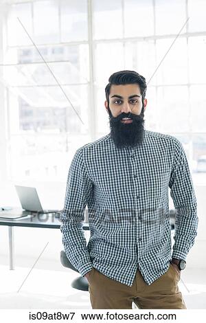 Bearded businessman with hands in pocket by office window View Large Photo Image Stock Photo - Bearded businessman with hands in pocket by office window. Fotosearch