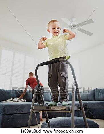Boy flexing muscle in living room, father in background View Large Photo Image Stock Image - Boy flexing muscle in living room, father in background. Fotosearch