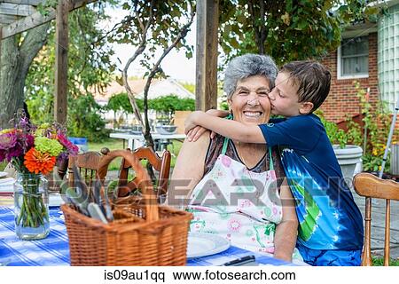 Stock Photography - Boy hugging and kissing grandmother's cheek at tomato eating festival. Fotosearch