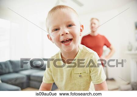 Boy smiling in living room, father in background View Large Photo Image Stock Image - Boy smiling in living room, father in background. Fotosearch