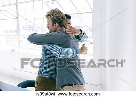 Stock Image - Business people hugging at meeting. Fotosearch