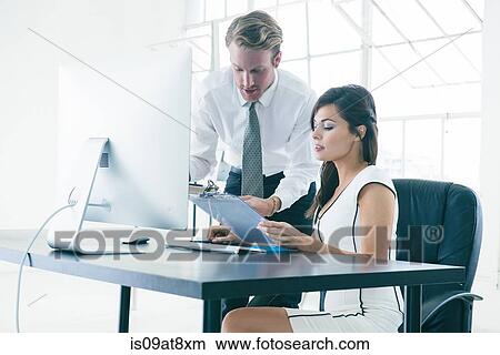Picture - Business people working on computer by office window. Fotosearch