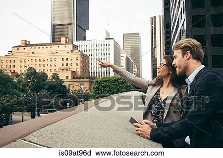 Stock Image - Businessman and woman pointing from walkway, Los Angeles, USA. Fotosearch