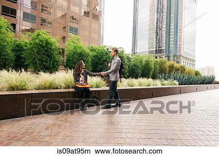 Businessman and woman shaking hands outside office building View Large Photo Image Picture - Businessman and woman shaking hands outside office building. Fotosearch