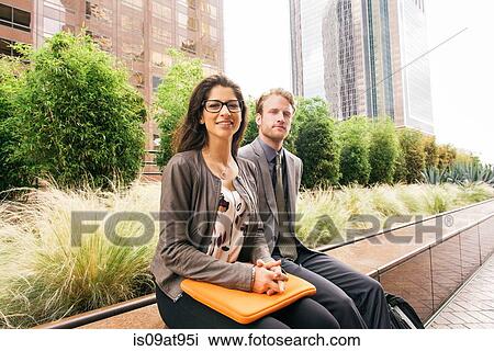 Businessman and woman sitting on wall with laptop in city View Large Photo Image Stock Image - Businessman and woman sitting on wall with laptop in city. Fotosearch