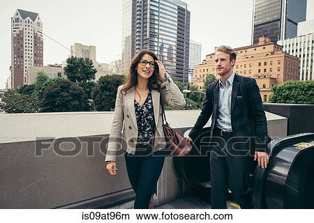 Businessman and woman stepping off escalator, Los Angeles, USA View Large Photo Image Picture - Businessman and woman stepping off escalator, Los Angeles, USA. Fotosearch