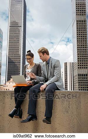 Businessman and woman using laptop on wall, Los Angeles, USA View Large Photo Image Stock Image - Businessman and woman using laptop on wall, Los Angeles, USA. Fotosearch