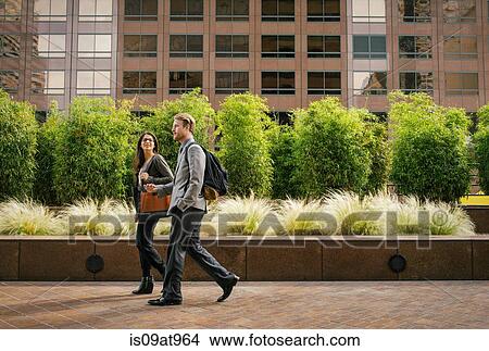 Businessman and woman walking and talking outside office buildings View Large Photo Image Picture - Businessman and woman walking and talking outside office buildings. Fotosearch