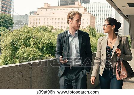 Stock Image - Businessman and woman walking and talking, Los Angeles, USA. Fotosearch