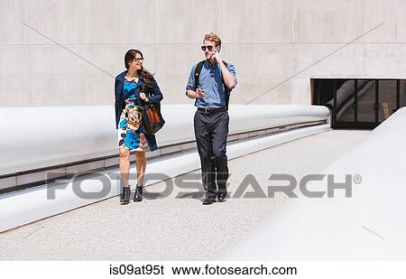Businessman and woman walking and talking in city View Large Photo Image Stock Photograph - Businessman and woman walking and talking in city. Fotosearch