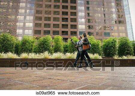 Businessman and woman walking outside office buildings View Large Photo Image Stock Photography - Businessman and woman walking outside office buildings. Fotosearch