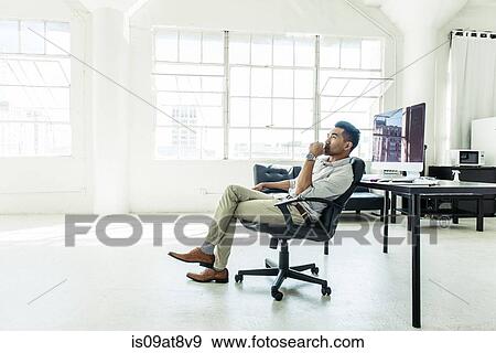 Stock Photo - Businessman contemplating by office window. Fotosearch