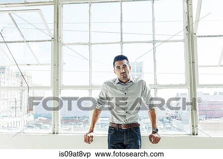 Businessman leaning against office window View Large Photo Image Stock Photography - Businessman leaning against office window. Fotosearch