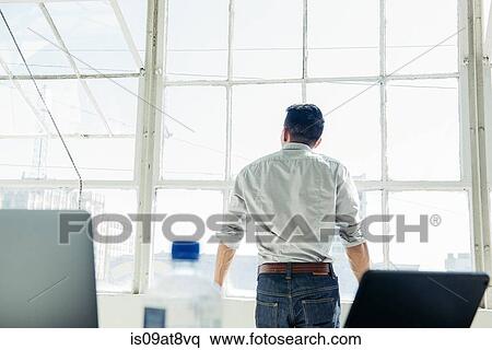 Businessman looking out of office window View Large Photo Image Stock Photography - Businessman looking out of office window. Fotosearch