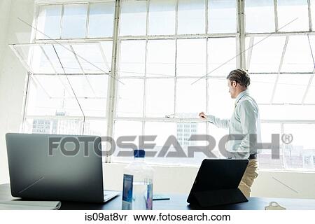 Businessman looking out of office window View Large Photo Image Stock Photography - Businessman looking out of office window. Fotosearch