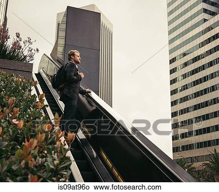 Businessman moving up escalator, Los Angeles, USA View Large Photo Image Picture - Businessman moving up escalator, Los Angeles, USA. Fotosearch