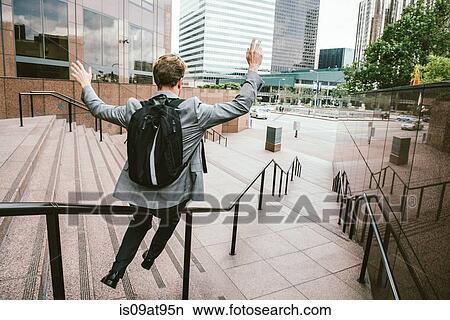 Businessman sliding down stair handrail, Los Angeles, USA View Large Photo Image Picture - Businessman sliding down stair handrail, Los Angeles, USA. Fotosearch