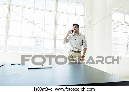 Businessman speaking on smartphone by office window View Large Photo Image Stock Image - Businessman speaking on smartphone by office window. Fotosearch