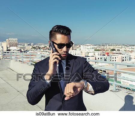 Businessman speaking on smartphone on roof terrace, Los Angeles, California, USA View Large Photo Image Picture - Businessman speaking on smartphone on roof terrace, Los Angeles, California, USA. Fotosearch