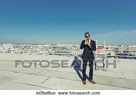 Businessman speaking on smartphone on roof terrace, Los Angeles, California, USA View Large Photo Image Picture - Businessman speaking on smartphone on roof terrace, Los Angeles, California, USA. Fotosearch