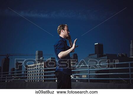Businessman speaking on smartphone on roof terrace, Los Angeles, California, USA View Large Photo Image Stock Photo - Businessman speaking on smartphone on roof terrace, Los Angeles, California, USA. Fotosearch
