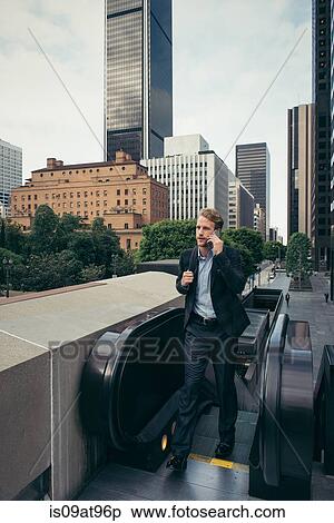 Businessman stepping off escalator, Los Angeles, USA View Large Photo Image Stock Photography - Businessman stepping off escalator, Los Angeles, USA. Fotosearch