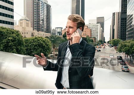 Businessman talking on smartphone from footbridge, Los Angeles, USA View Large Photo Image Stock Photo - Businessman talking on smartphone from footbridge, Los Angeles, USA. Fotosearch