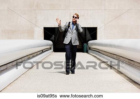 Businessman talking on smartphone on walkway View Large Photo Image Stock Photograph - Businessman talking on smartphone on walkway. Fotosearch