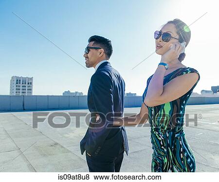 Stock Photo - Businessman with businesswoman using smartphone on roof terrace, Los Angeles, California, USA. Fotosearch