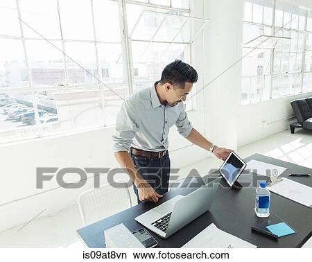 Businessman working on laptop by office window View Large Photo Image Picture - Businessman working on laptop by office window. Fotosearch