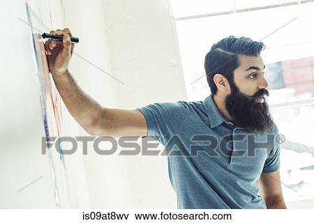 Stock Photo - Businessman writing on wall chart in office. Fotosearch