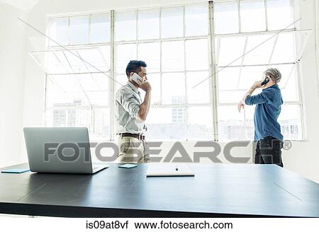 Businessmen speaking on smartphone by office window View Large Photo Image Stock Image - Businessmen speaking on smartphone by office window. Fotosearch