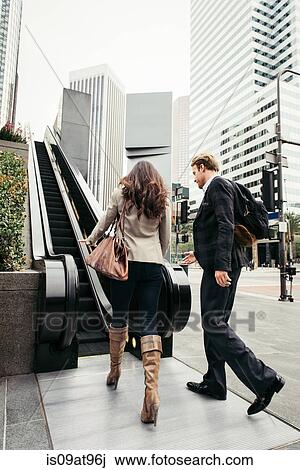 Businesswoman and man walking toward escalator, Los Angeles, USA View Large Photo Image Stock Image - Businesswoman and man walking toward escalator, Los Angeles, USA. Fotosearch