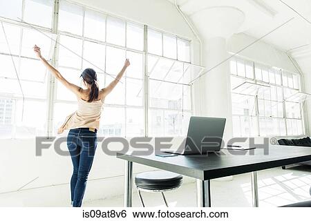 Stock Photograph - Businesswoman dancing by office window. Fotosearch