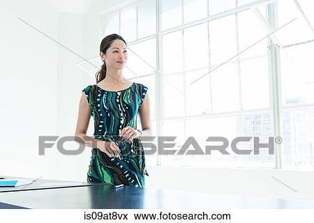 Businesswoman in patterned dress by office window View Large Photo Image Stock Photo - Businesswoman in patterned dress by office window. Fotosearch