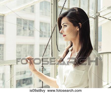 Businesswoman looking out of office window View Large Photo Image Stock Photo - Businesswoman looking out of office window. Fotosearch