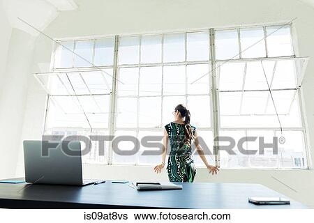 Businesswoman looking out of office window View Large Photo Image Stock Photograph - Businesswoman looking out of office window. Fotosearch