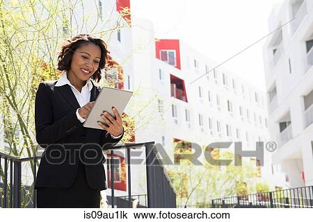 Stock Image - Businesswoman using digital tablet, outdoors. Fotosearch