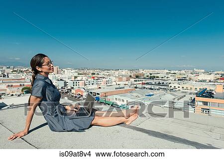 Businesswoman using laptop on roof terrace, Los Angeles, California, USA View Large Photo Image Picture - Businesswoman using laptop on roof terrace, Los Angeles, California, USA. Fotosearch
