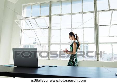 Stock Photograph - Businesswoman working by office window. Fotosearch