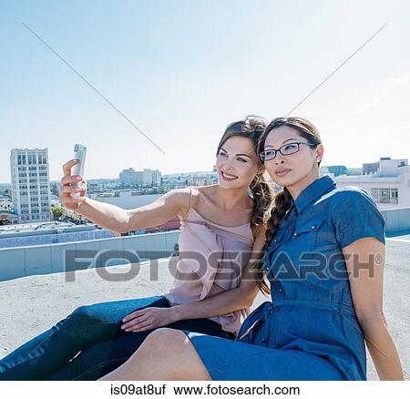Businesswomen taking selfie with smartphone on roof terrace, Los Angeles, California, USA View Large Photo Image Stock Image - Businesswomen taking selfie with smartphone on roof terrace, Los Angeles, California, USA. Fotosearch