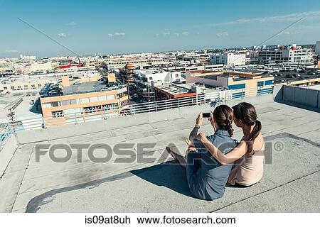 Businesswomen taking selfie with smartphone on roof terrace, Los Angeles, California, USA View Large Photo Image Stock Image - Businesswomen taking selfie with smartphone on roof terrace, Los Angeles, California, USA. Fotosearch